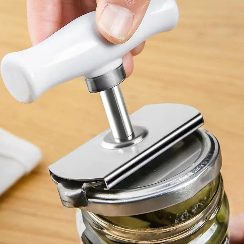 A hand is using a stainless steel multi-function bottle cap opener to open a glass jar.
