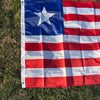 A decorative banner displaying the flag of Liberia, featuring blue, white, and red stripes and a white star on a green lawn.