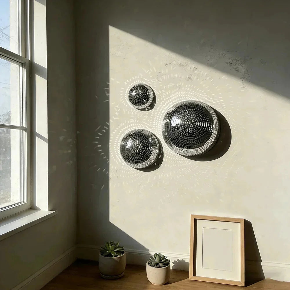 Décor mural avec trois boules de verre disco rondes sur un mur clair près d'une fenêtre.