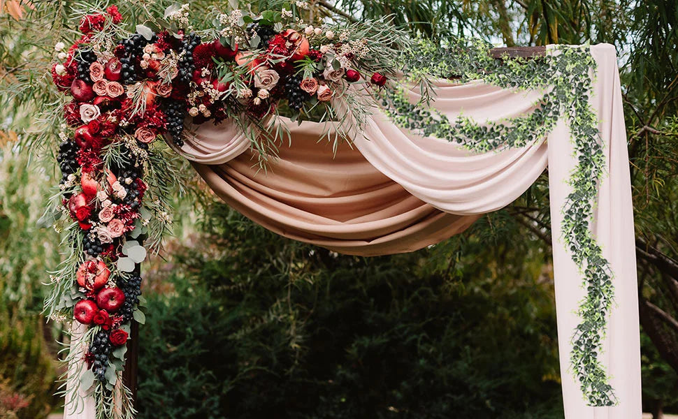 Arche florale décorée de baies rouges profondes, de roses et de guirlandes d'eucalyptus vert pour un décor d'événement.