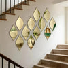 A decorative wall display featuring ten teardrop-shaped reflective acrylic mirrors mounted on a white wall above a wooden sta