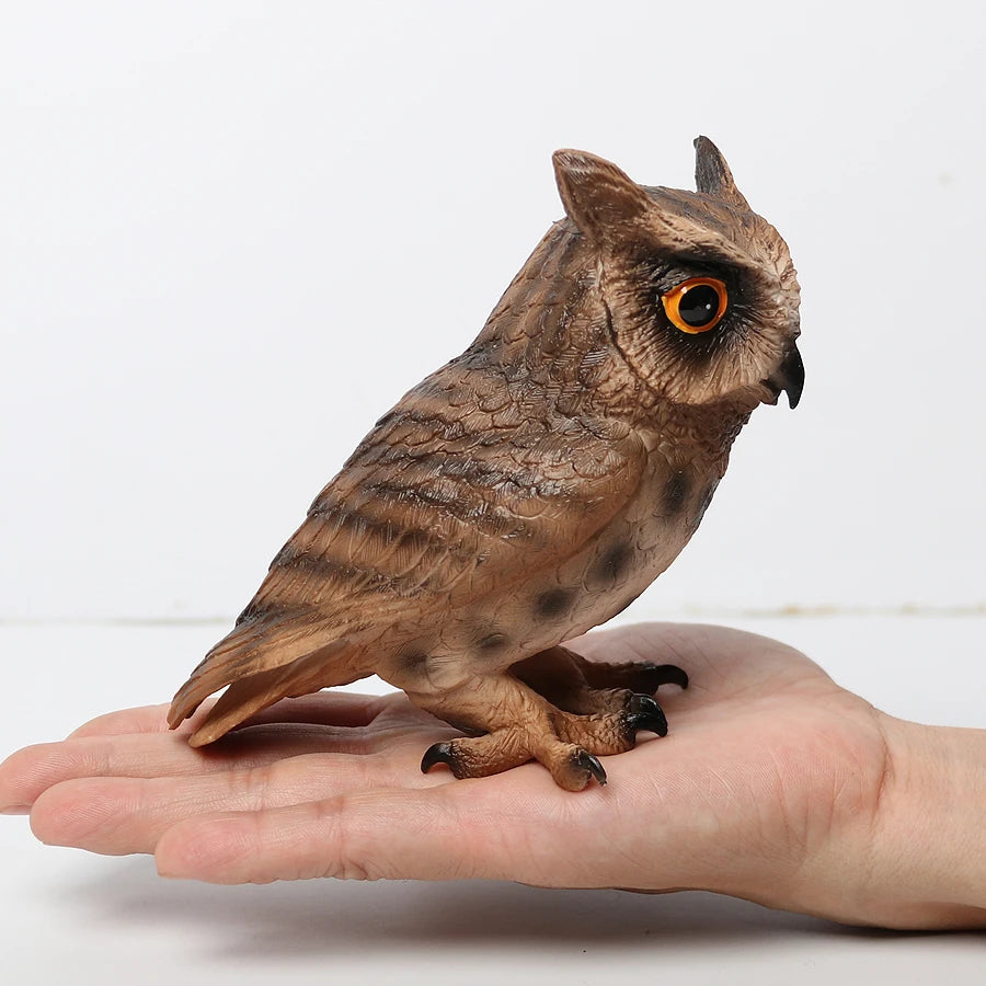 A realistic figurine of an owl perched on a human hand.