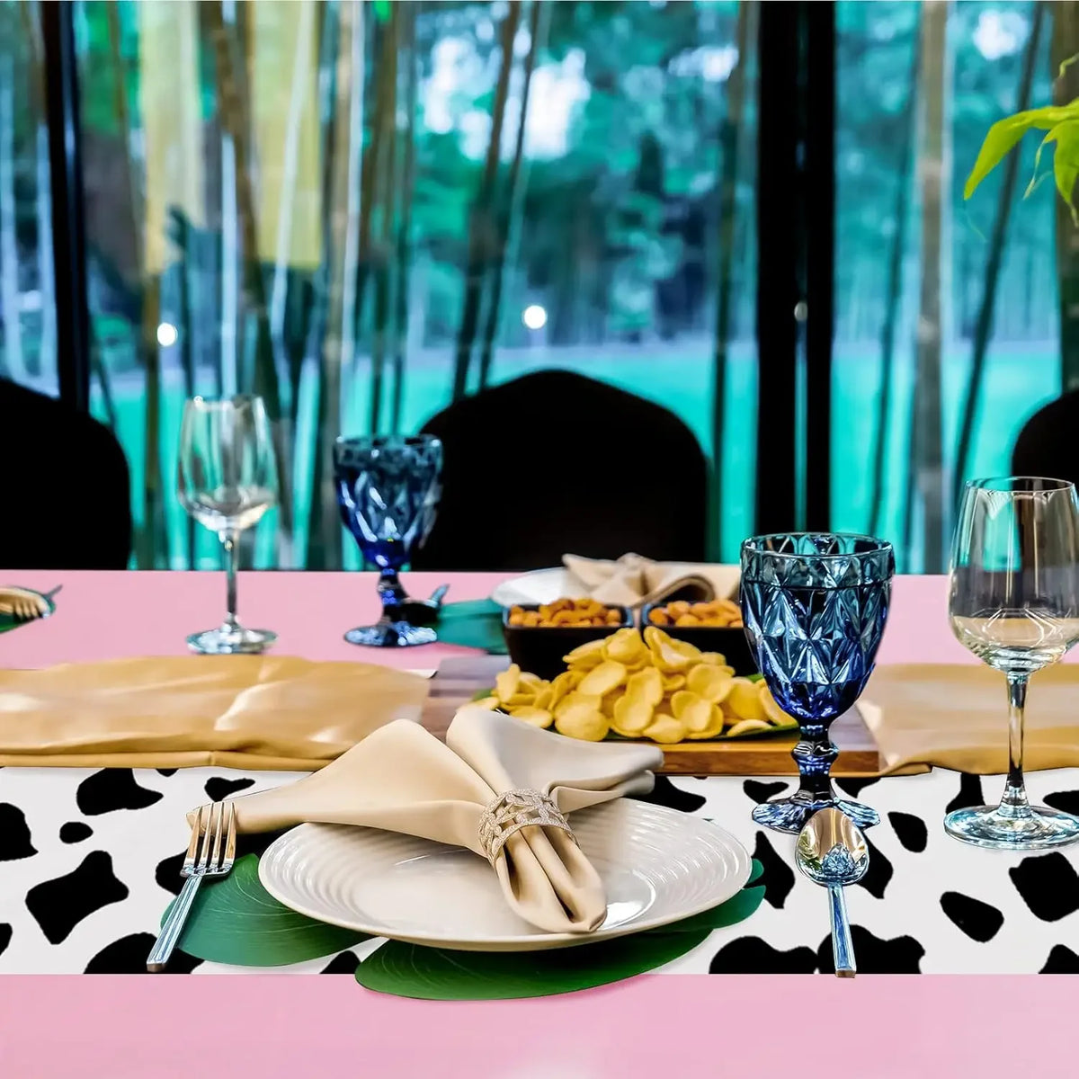 Pink cow print western tablecloth set with gold and silver tableware on a pink table.