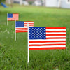 Three small American flags on sticks standing in green grass.