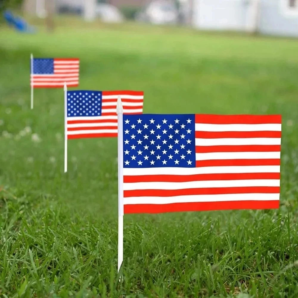 Three small American flags on sticks standing in green grass.