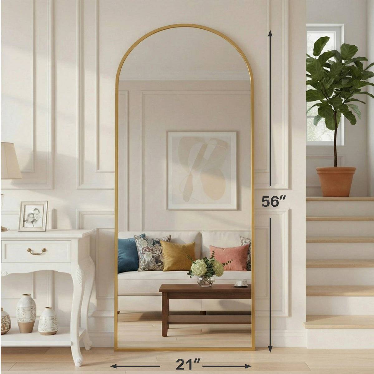 A full length body mirror with a gold aluminum frame reflecting a room interior and a potted plant.