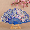 A blue and pink silk flower folding fan displayed on a wooden stand against a beige background.