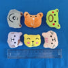A collection of five small, fuzzy plush animal dolls in various colors including gray, orange, green, pink, and yellow, laid 