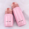 A pink vacuum insulated coffee mug with a pink lid and a black text Good Luck printed on the side.