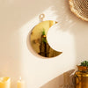 A gold moon acrylic wall mirror with a loop hanger mounted on a beige wall.