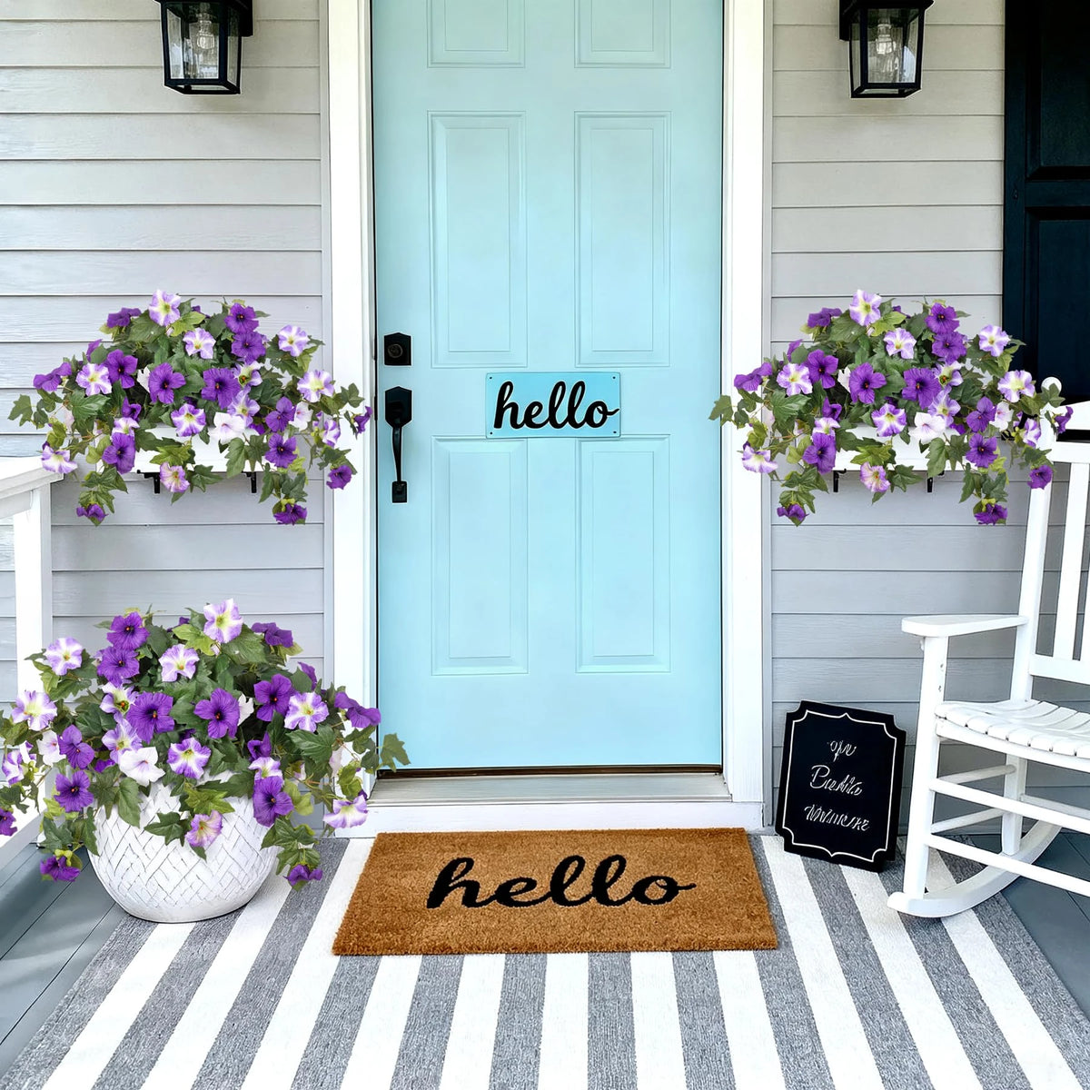 A light blue door decorated with purple petunia bundles and a welcome mat that says hello