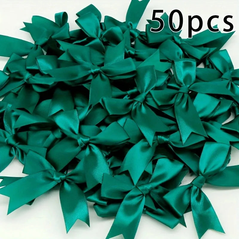 A pile of 50 emerald green satin ribbon bows for gift wrapping and decor.