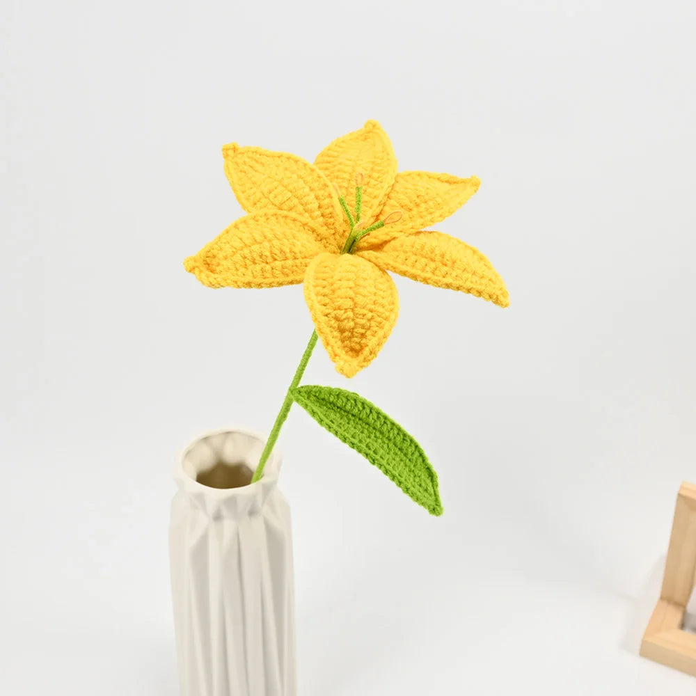 Hand-crocheted yellow lily flowers with green stems displayed in a white vase.