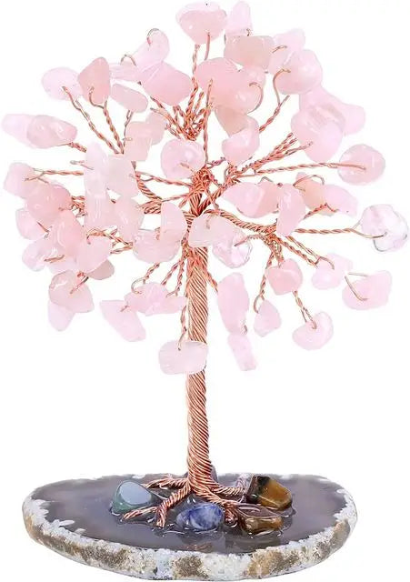 A crystal money tree decor featuring pink quartz crystals on a wooden branch set in a stone base.