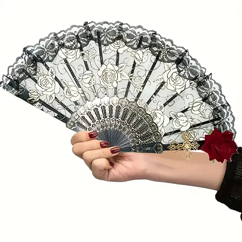 A hand holds a vintage black and white floral folding fan with lace edges and a gold accent.