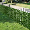 A long row of artificial ivy hedge fence panels lining a walkway and lawn.