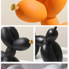 A set of modern resin sculptures shaped like balloons in orange, black, and white.