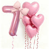 Pink heart-shaped balloons forming the number 1 with pink bows and red ribbons for party decor