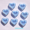 A collection of light blue heart-shaped acrylic charms casting shadows on a white surface.