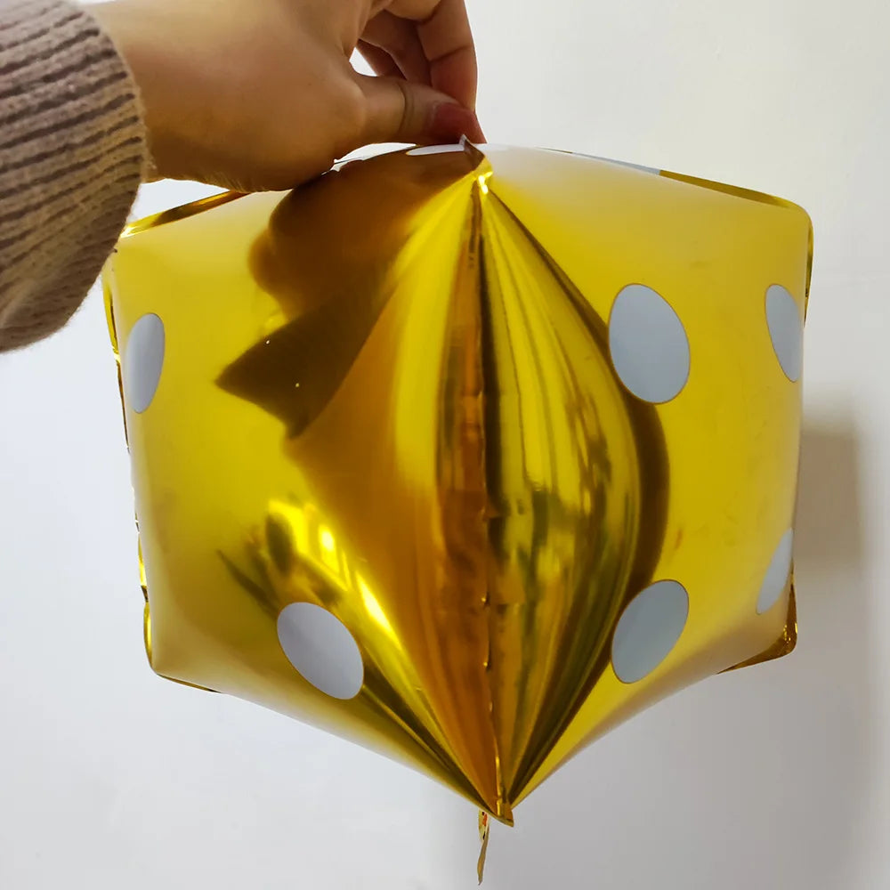 A close-up of a gold foil balloon decorated with white polka dots being held by a hand.