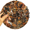 A hand holds an orange sticker featuring a skull and crossbones design on a dark background.