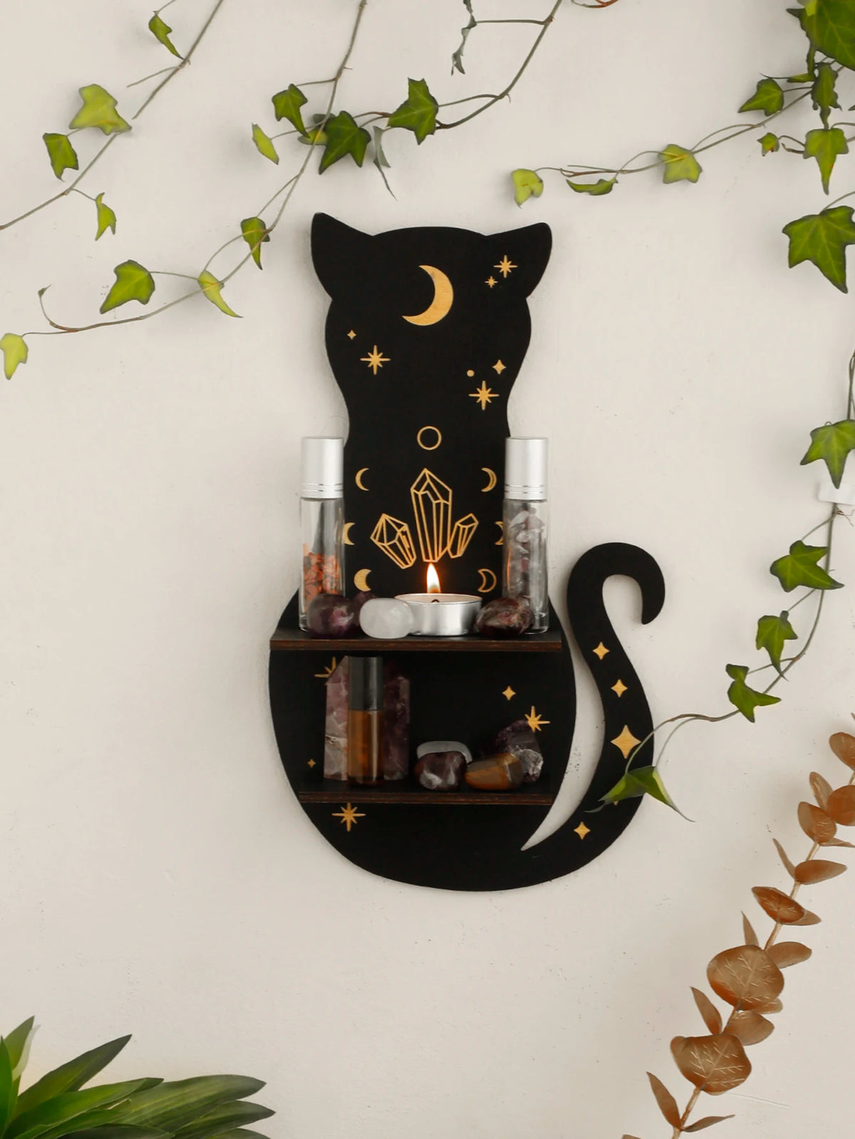 A black cat silhouette with a crescent moon sits above a dark shelf displaying various crystals and a candle.