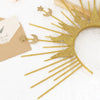 A gold celestial halo headband with sun rays and silver star accents resting on a light background.