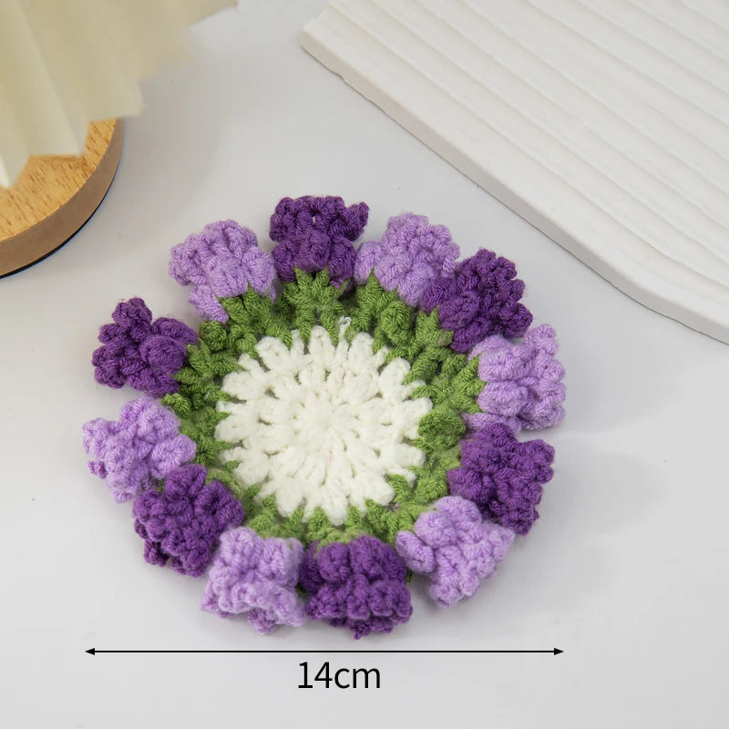 Hand-crocheted rose flower coasters featuring purple and green yarn petals.