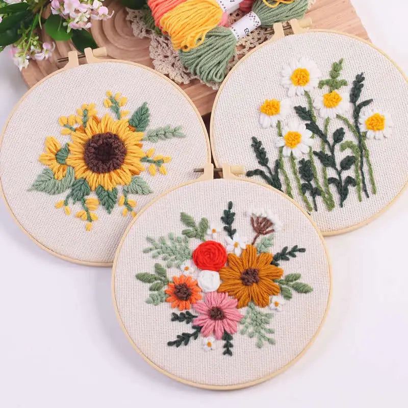 Punch needle embroidery kit featuring floral designs of sunflowers and daisies on a beige cloth