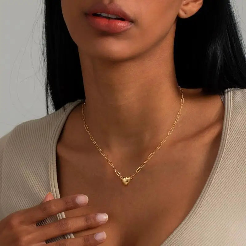 A close-up of a woman wearing a gold plated heart pendant necklace on her neck.