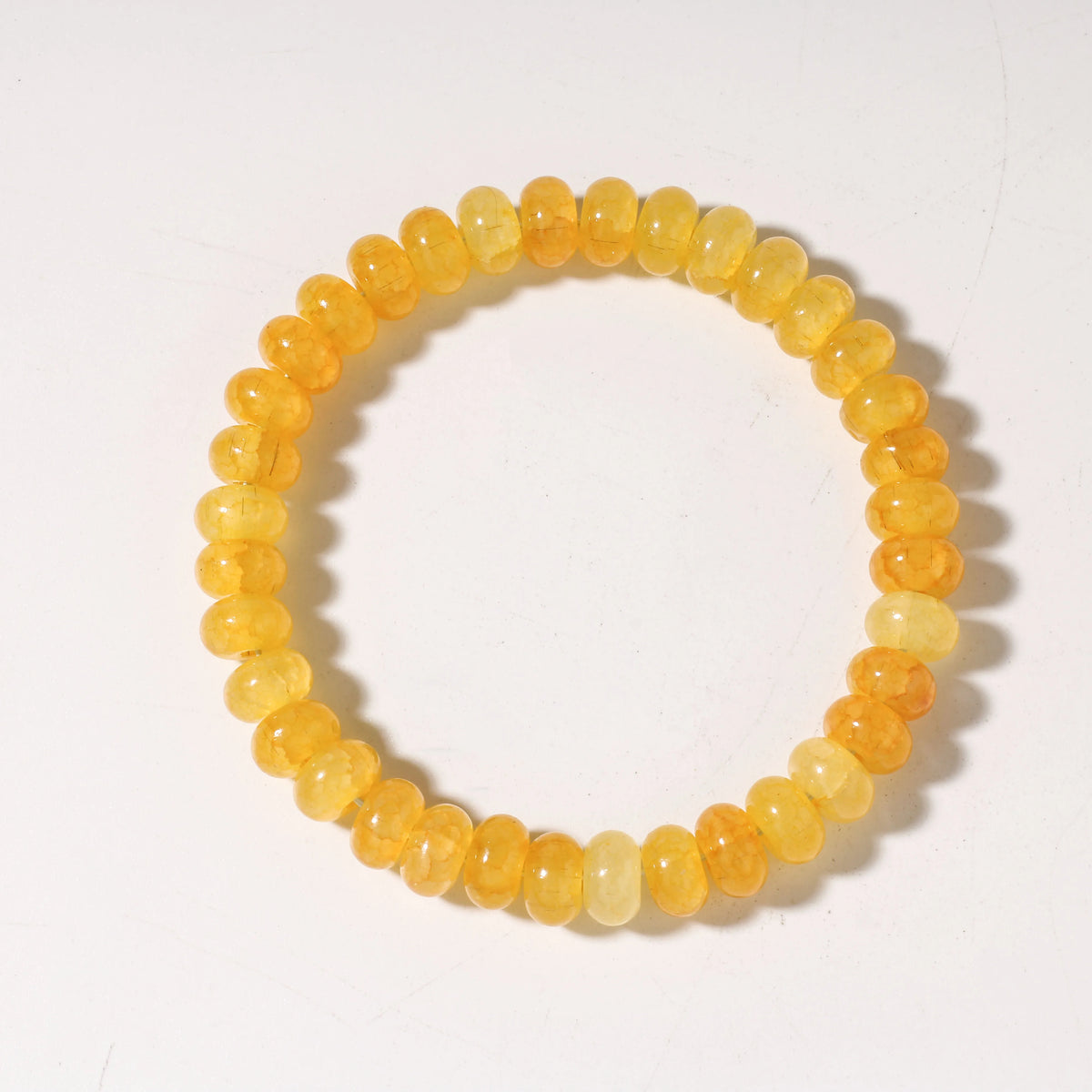 A bracelet made of round, translucent yellow-orange citrine crystals.
