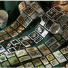A collection of decorative washi tape squares in various natural and vintage patterns arranged on a green fabric.