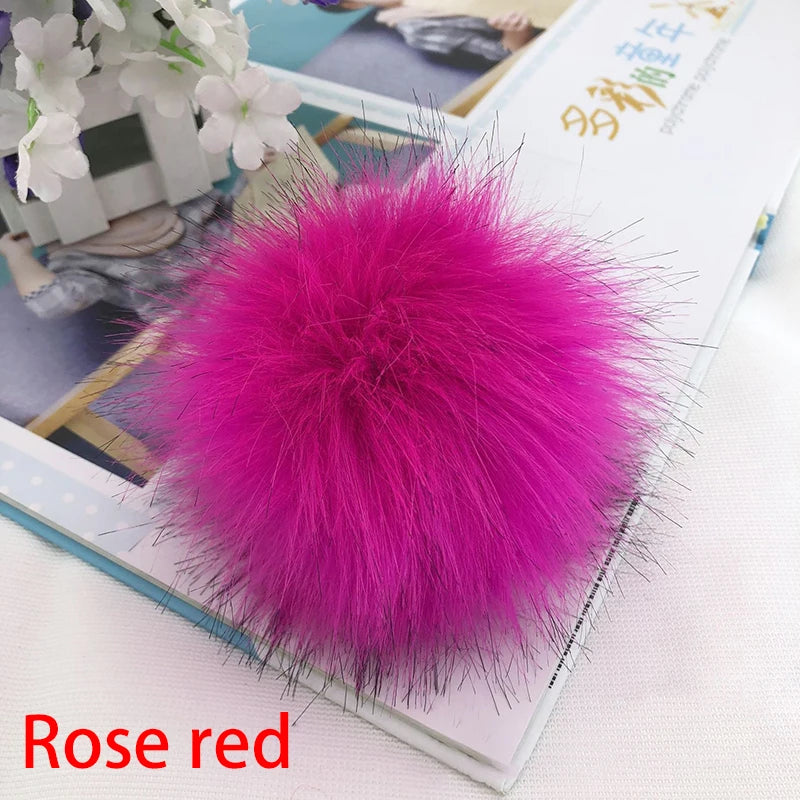 Pompon en fourrure rouge rose vif pour cheveux, exposé sur une surface claire.