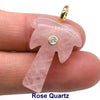A pink rose quartz crystal pendant with a zircon charm is shown being held by a person's finger.