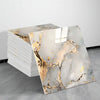 A stack of self-adhesive marble tile stickers featuring gold veining on a white marble background.