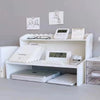 A white two-layer desktop organizer shelf featuring a laptop, keyboard, and various stationery items.