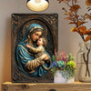 A metal sign depicting the Virgin Mary holding the infant Jesus, rendered in bronze tones.