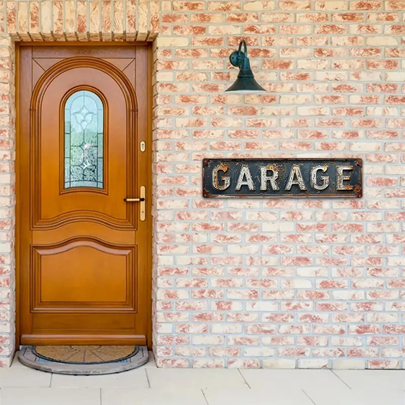 A vintage metal garage sign with a rooster silhouette is mounted on a light-colored brick wall above a wooden door.