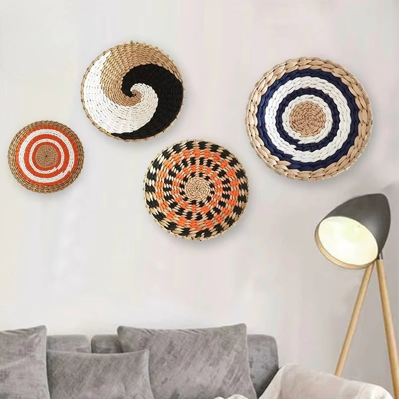 A collection of round woven straw wall decor pieces in various concentric patterns hanging on a white wall.