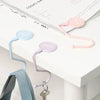 Pink and blue heavy duty purse and bag hooks displayed on a white surface next to a document.