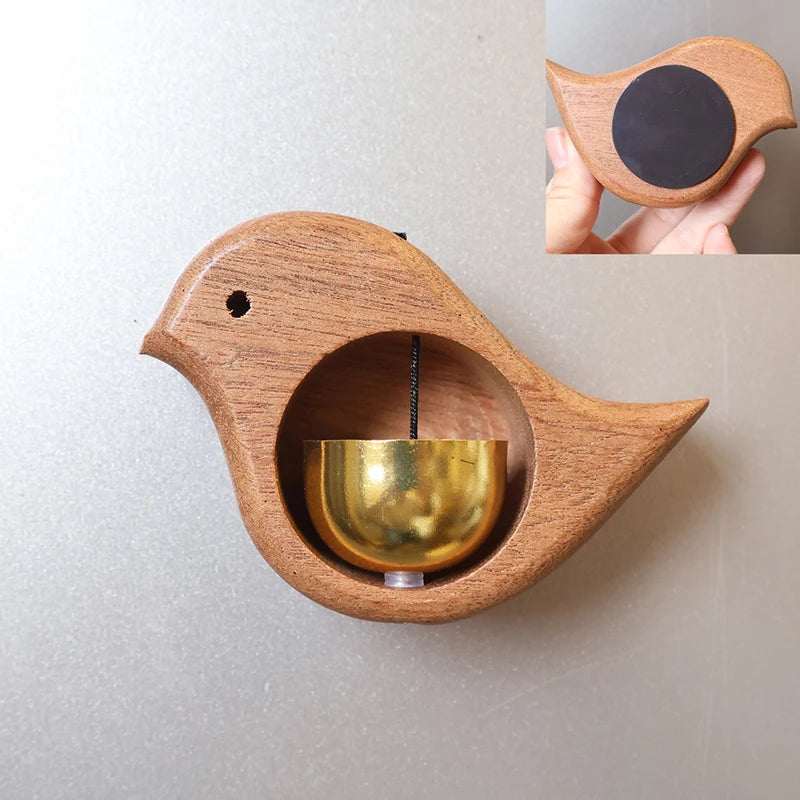 A wooden doorbell shaped like a bird with a brass chime inside, mounted on a wall.