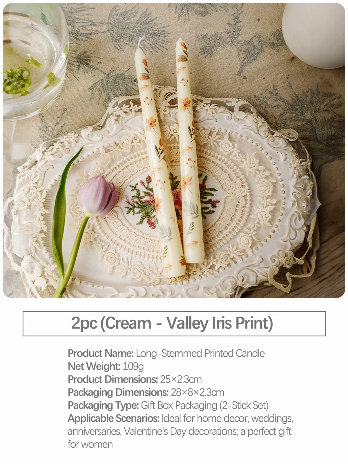 Two long-stemmed printed candles in cream with iris floral designs displayed on a lace platter.