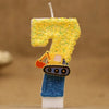 A yellow glitter cake candle shaped like the number 7, mounted on a blue base.