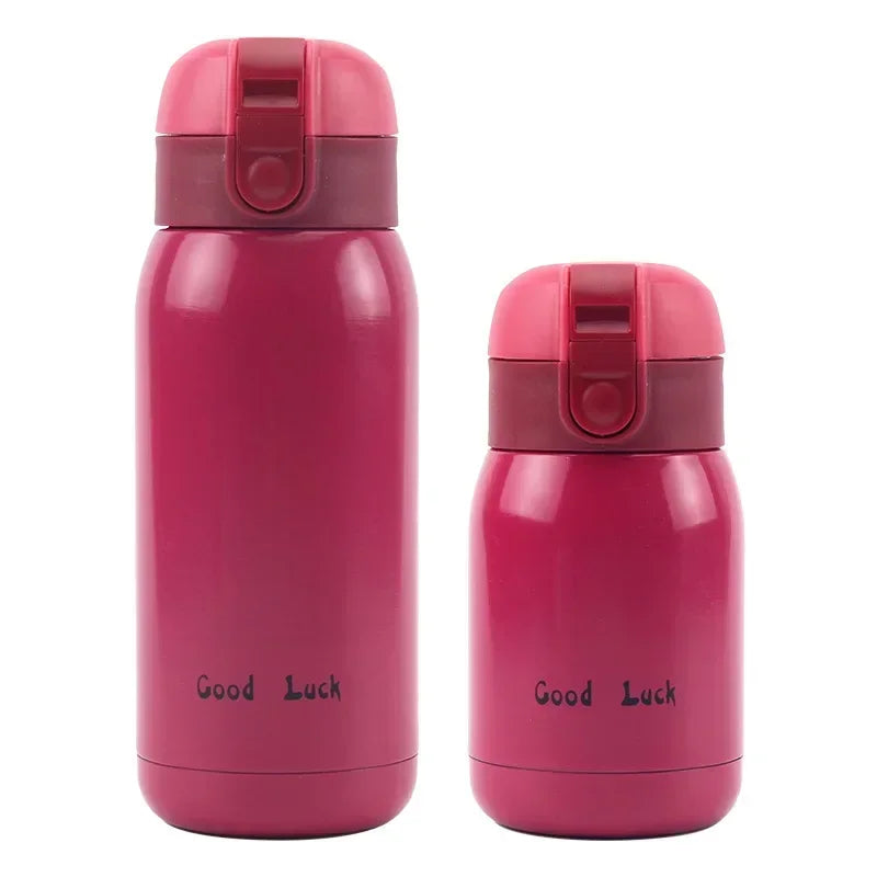 A pink vacuum insulated coffee mug with a red lid and Good Luck text printed on the body.