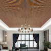 Interior view of a room featuring a ceiling panel design with vertical wood grain slats and a chandelier.