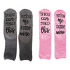 Four fuzzy slippers with funny wine quotes on them in gray and pink colors
