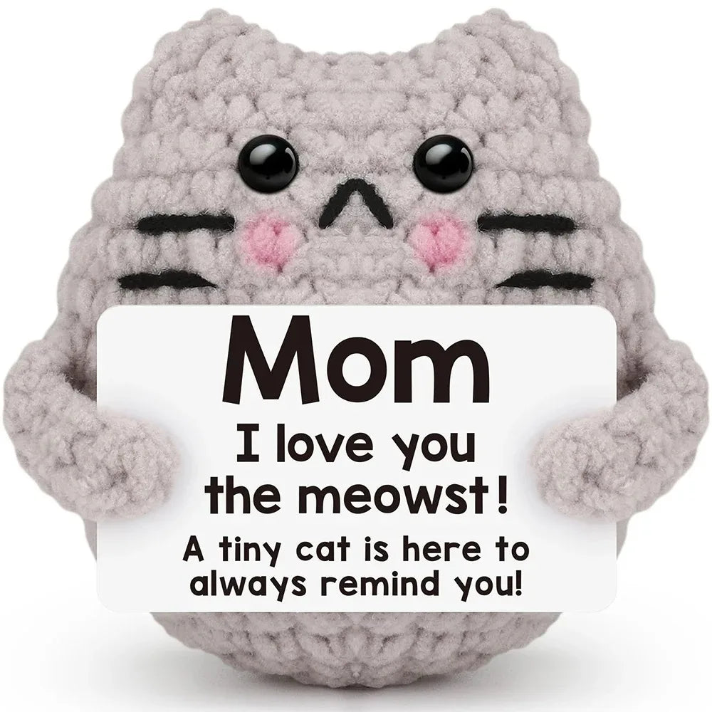 A handcrafted crochet cat doll made of gray yarn with black markings and pink accents.