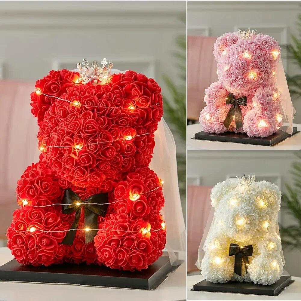 Artificial rose teddy bear in red and pink, decorated with fairy lights and a crown.