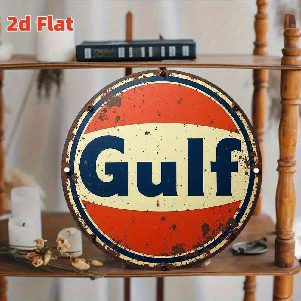 A vintage round metal sign with an orange and blue color scheme featuring the word Gulf on a wooden shelf.
