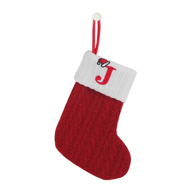 Red knitted sock ornament with a white cuff featuring a red letter J hanging from a string.